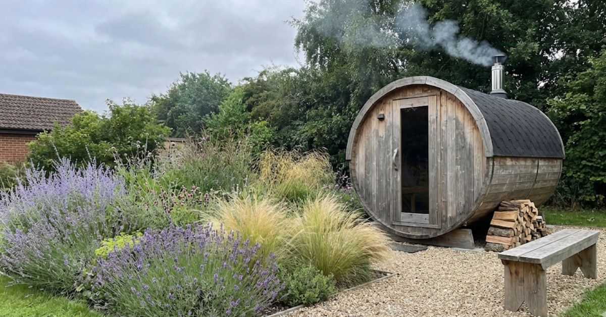 A modern wood-burning outdoor sauna in a lush backyard wellness garden.