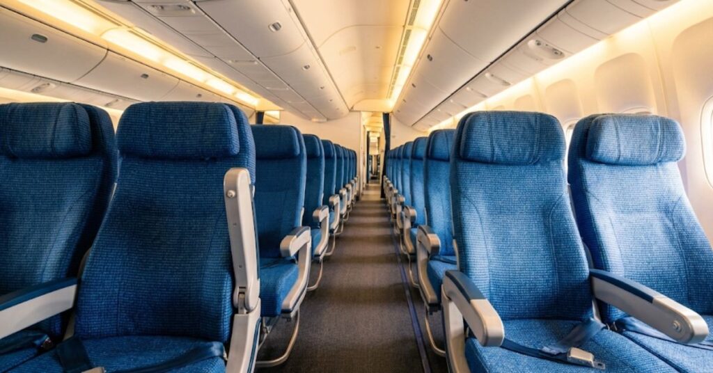 An airplane aisle with one armrest raised to show extra space.